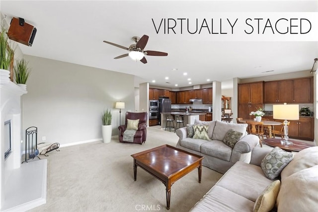 living room with a ceiling fan, baseboards, recessed lighting, light carpet, and a glass covered fireplace