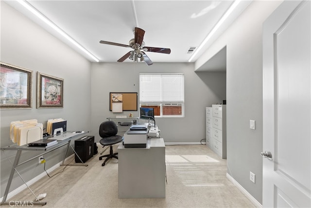 office space with baseboards, a ceiling fan, visible vents, and light carpet