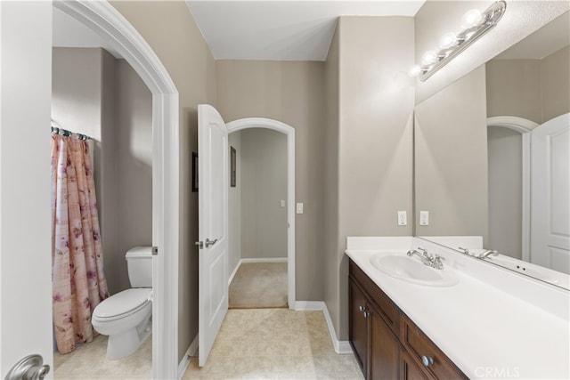 bathroom with toilet, vanity, and baseboards