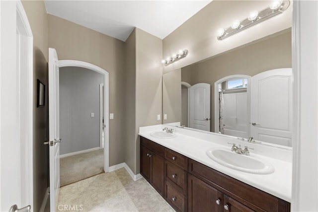 full bathroom featuring double vanity, baseboards, and a sink