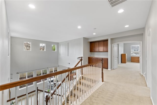 hall with visible vents, light colored carpet, an upstairs landing, recessed lighting, and arched walkways