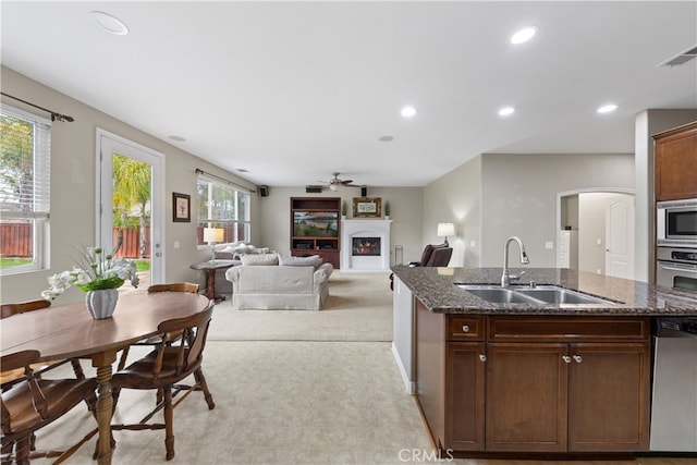 kitchen featuring visible vents, recessed lighting, a warm lit fireplace, a sink, and appliances with stainless steel finishes