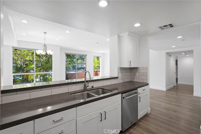 kitchen with dark countertops, visible vents, tasteful backsplash, stainless steel dishwasher, and a sink