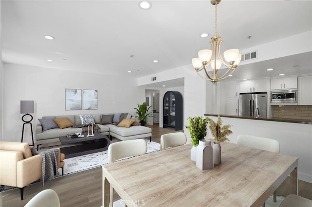 dining area with a chandelier, visible vents, recessed lighting, and wood finished floors