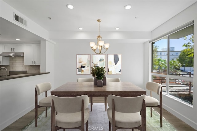 dining space featuring light wood finished floors, visible vents, baseboards, recessed lighting, and a notable chandelier