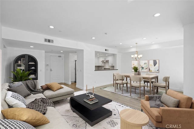 living room with recessed lighting, visible vents, an inviting chandelier, and light wood-style flooring