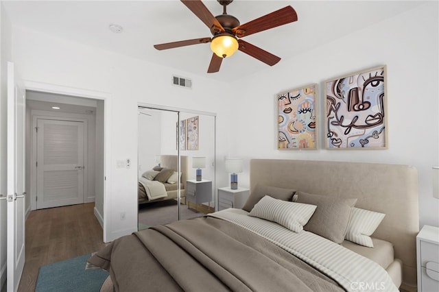 bedroom with visible vents, wood finished floors, a closet, baseboards, and ceiling fan