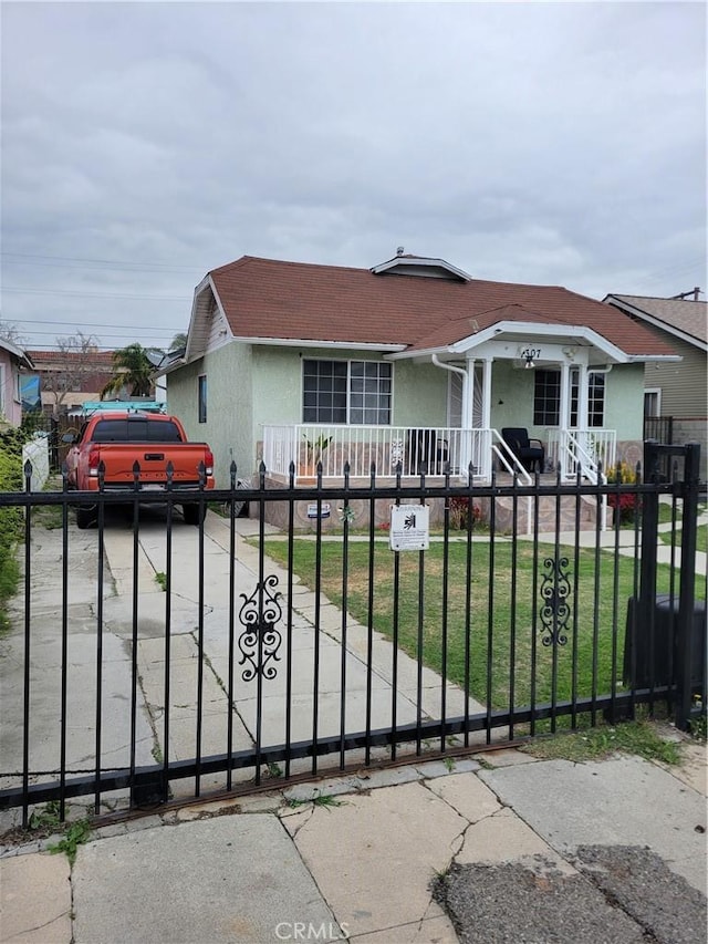 view of front facade with a fenced front yard, stucco siding, a front yard, and a gate