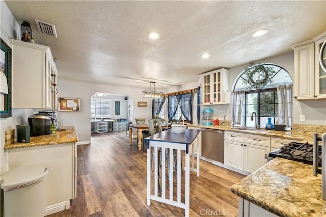 kitchen featuring visible vents, glass insert cabinets, appliances with stainless steel finishes, wood finished floors, and a sink