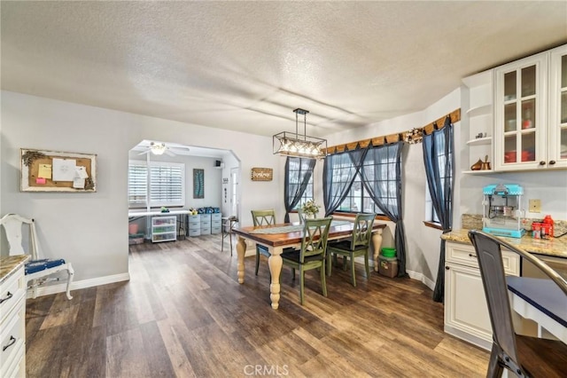 dining room featuring ceiling fan, wood finished floors, baseboards, and a textured ceiling