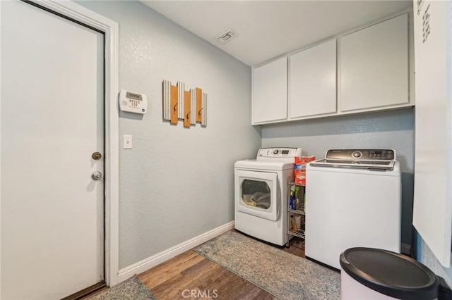 laundry area with wood finished floors, baseboards, visible vents, cabinet space, and washer and dryer