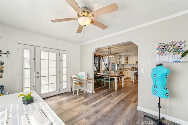 interior space featuring arched walkways, ornamental molding, baseboards, and wood finished floors