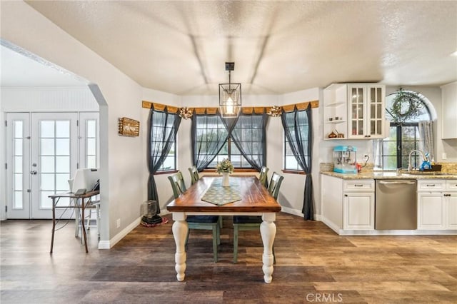 dining area with a textured ceiling, wood finished floors, arched walkways, and baseboards