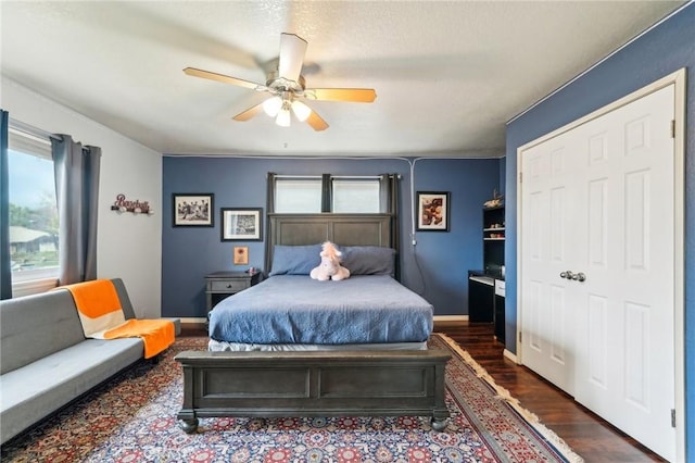 bedroom with a ceiling fan, multiple windows, dark wood-style floors, and baseboards