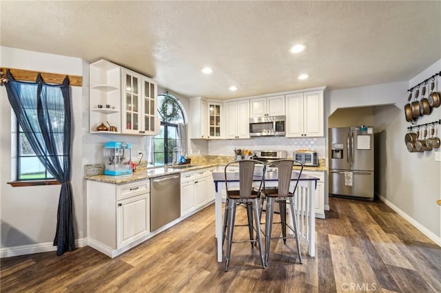 kitchen with a sink, stainless steel appliances, tasteful backsplash, and white cabinetry