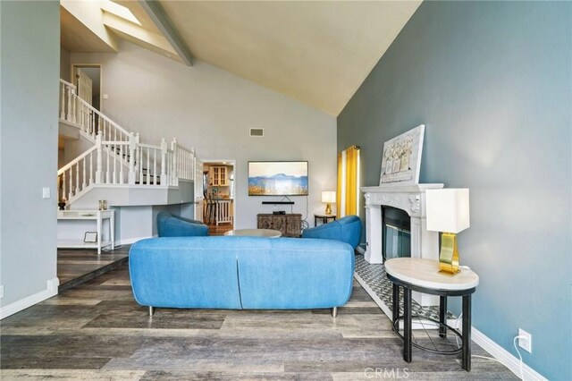 living area with baseboards, wood finished floors, a glass covered fireplace, and stairway