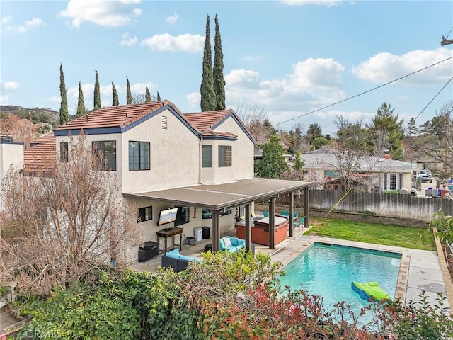 rear view of house with stucco siding, an outdoor living space, a patio, a fenced backyard, and a hot tub