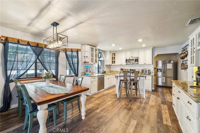 dining space featuring dark wood-style floors, visible vents, a toaster, recessed lighting, and a textured ceiling