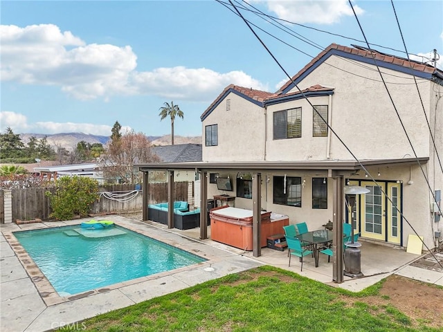 back of property featuring a patio area, stucco siding, a hot tub, and a fenced backyard