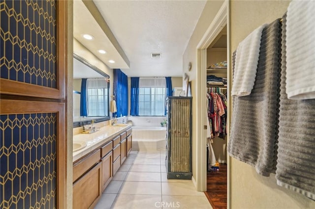 full bath with tile patterned floors, visible vents, a textured ceiling, double vanity, and a bath