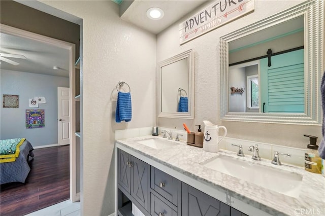 bathroom with a sink, wood finished floors, ceiling fan, and double vanity