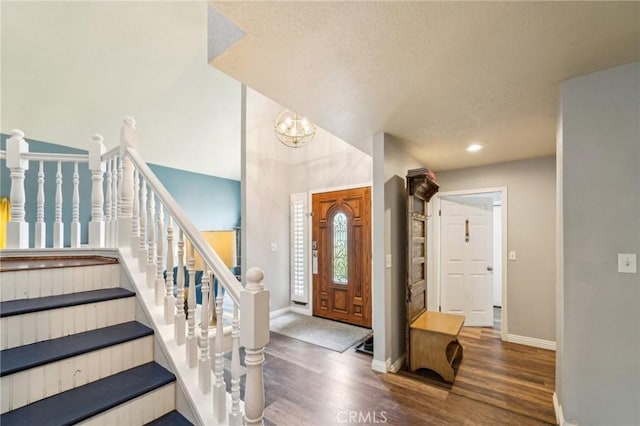 entryway featuring stairs, an inviting chandelier, wood finished floors, and baseboards