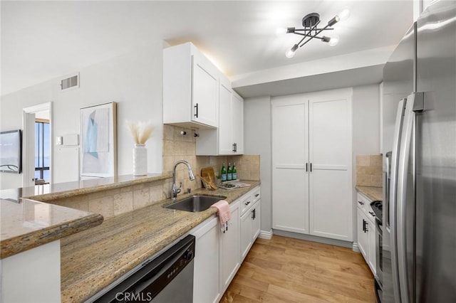 kitchen with visible vents, light wood finished floors, a sink, stainless steel appliances, and white cabinets