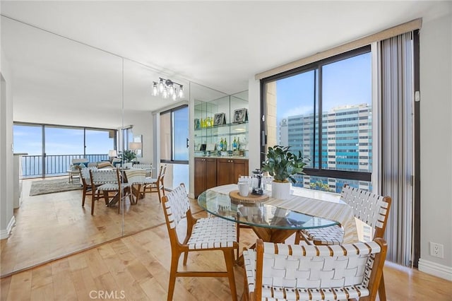 dining area featuring a wall of windows, a wealth of natural light, and light wood finished floors