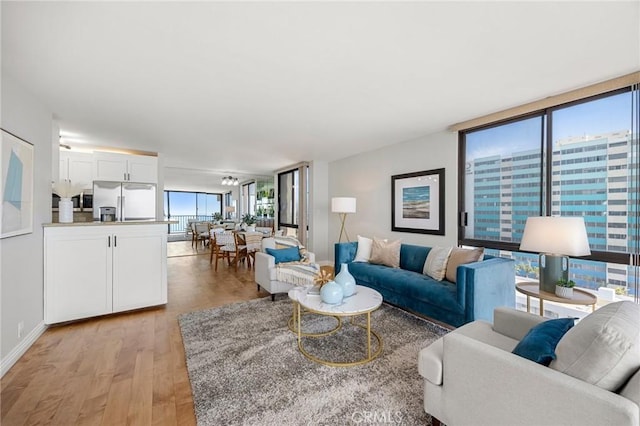 living room with light wood finished floors, floor to ceiling windows, and baseboards