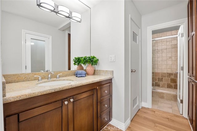 bathroom with vanity, wood finished floors, visible vents, baseboards, and a stall shower