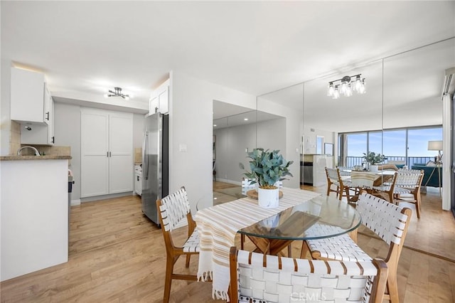 dining area with a wall of windows, light wood-type flooring, and baseboards