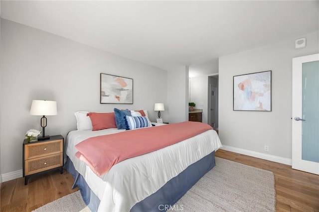 bedroom featuring ensuite bath, wood finished floors, and baseboards