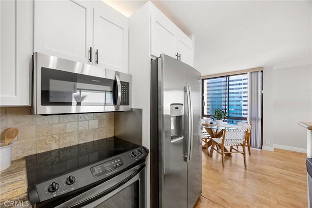 kitchen with baseboards, decorative backsplash, light wood-style floors, white cabinets, and stainless steel appliances