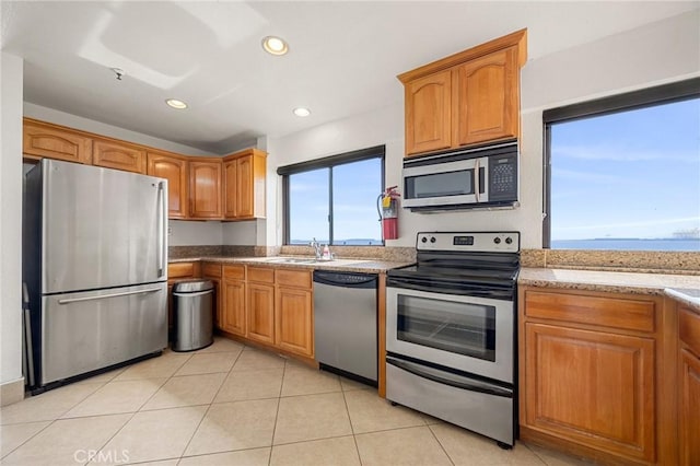 kitchen with brown cabinets, a sink, recessed lighting, stainless steel appliances, and light tile patterned floors