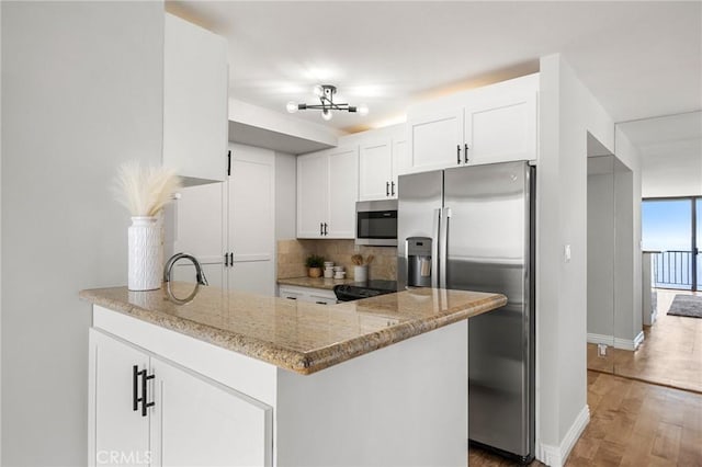 kitchen with light wood-type flooring, light stone counters, tasteful backsplash, stainless steel appliances, and white cabinets