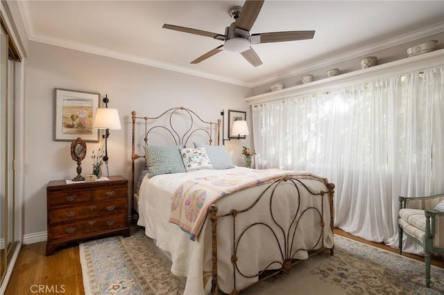 bedroom featuring ceiling fan, a closet, wood finished floors, and crown molding