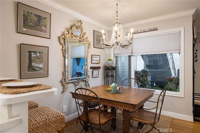 dining room with a notable chandelier, wood finished floors, baseboards, and ornamental molding