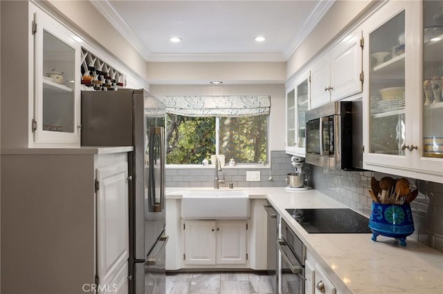 kitchen with crown molding, decorative backsplash, stainless steel appliances, white cabinetry, and a sink