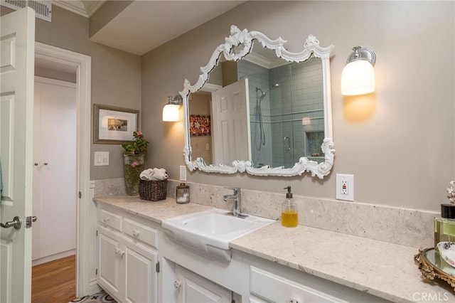 full bath featuring vanity, a shower stall, wood finished floors, and visible vents