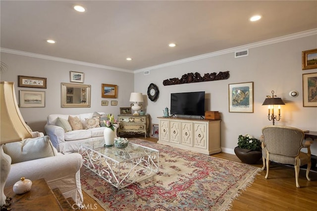 living room with visible vents, wood finished floors, and ornamental molding