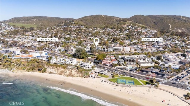 drone / aerial view with a water and mountain view and a view of the beach