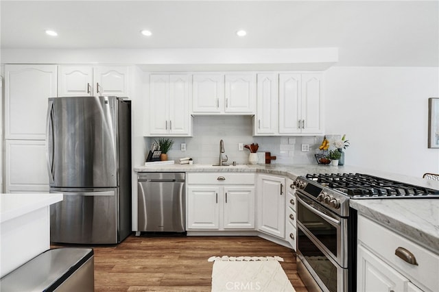 kitchen with white cabinetry, a sink, wood finished floors, and stainless steel appliances