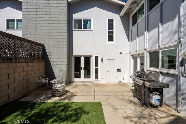 rear view of house featuring french doors, a patio, fence, and stucco siding