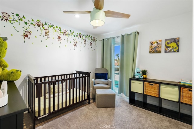 bedroom with a nursery area, ceiling fan, and carpet flooring