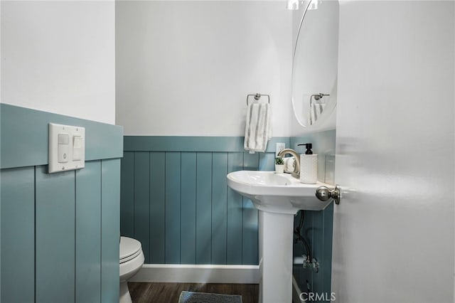 half bathroom featuring wainscoting, toilet, and wood finished floors