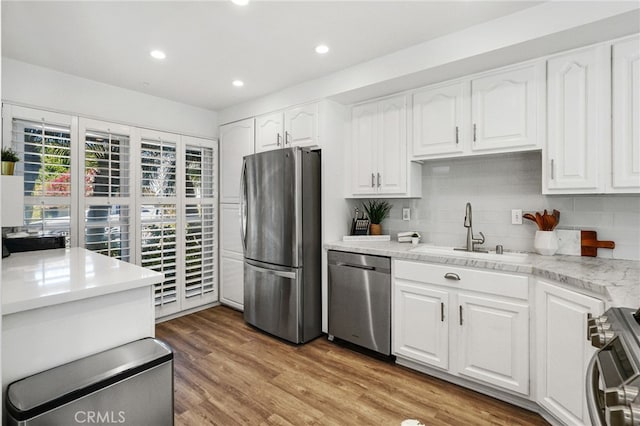 kitchen featuring a sink, stainless steel appliances, light wood-style floors, white cabinets, and light countertops