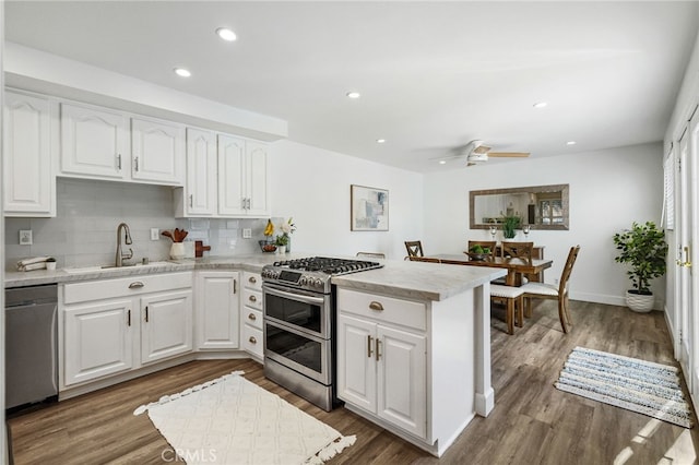 kitchen featuring a sink, appliances with stainless steel finishes, a peninsula, white cabinets, and light countertops