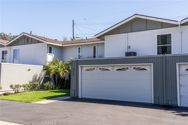 view of front of home featuring a garage, central air condition unit, and fence