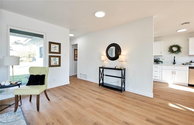 living area featuring visible vents, light wood-type flooring, and baseboards