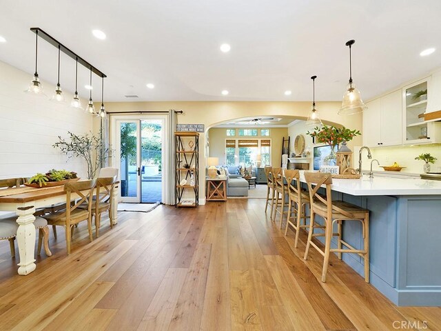 kitchen with light countertops, light wood-style flooring, plenty of natural light, and arched walkways